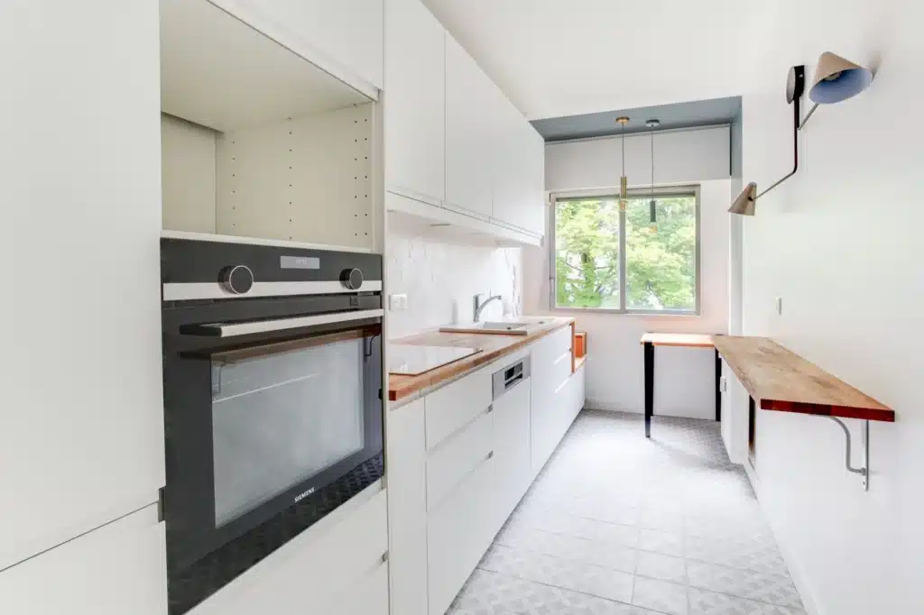 Cuisine en longueur blanche avec plan de travail en bois, rénovée par Azurix